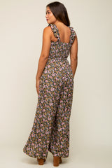 woman wearing a black floral maternity jumpsuit with ruffled straps, showing a side view and soft silhouette