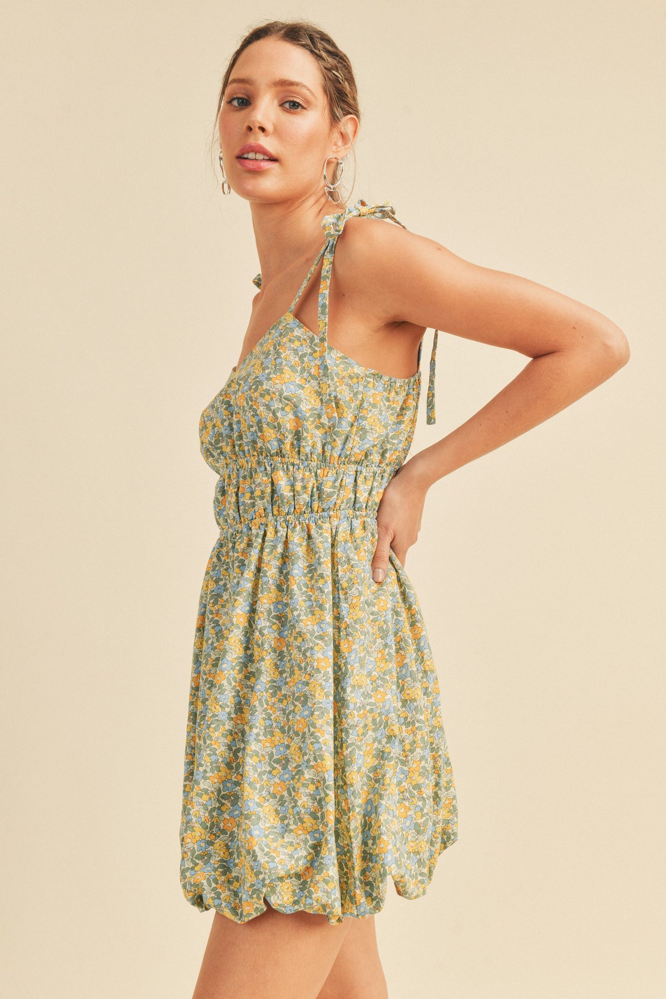 woman wearing a light green floral mini dress with tie straps and a smocked bodice