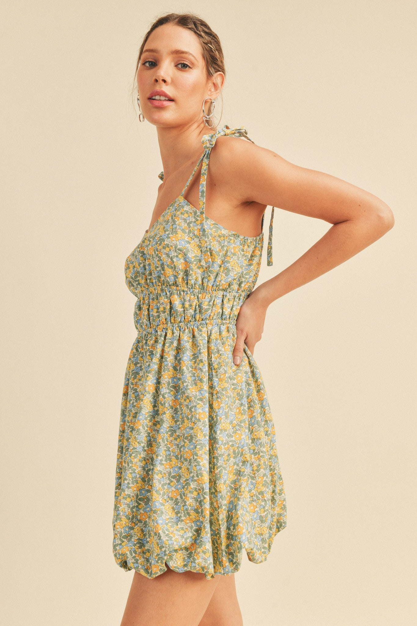 woman wearing a light green floral mini dress with tie straps and a smocked bodice