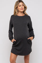 woman wearing a black striped long sleeve maternity dress with pockets and a visible baby bump