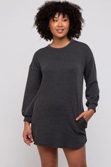 woman wearing a loose-fitting black and gray striped long sleeve sweater dress with side pockets