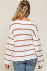 back view of woman wearing white and brown striped long sleeve knit sweater with blue jeans