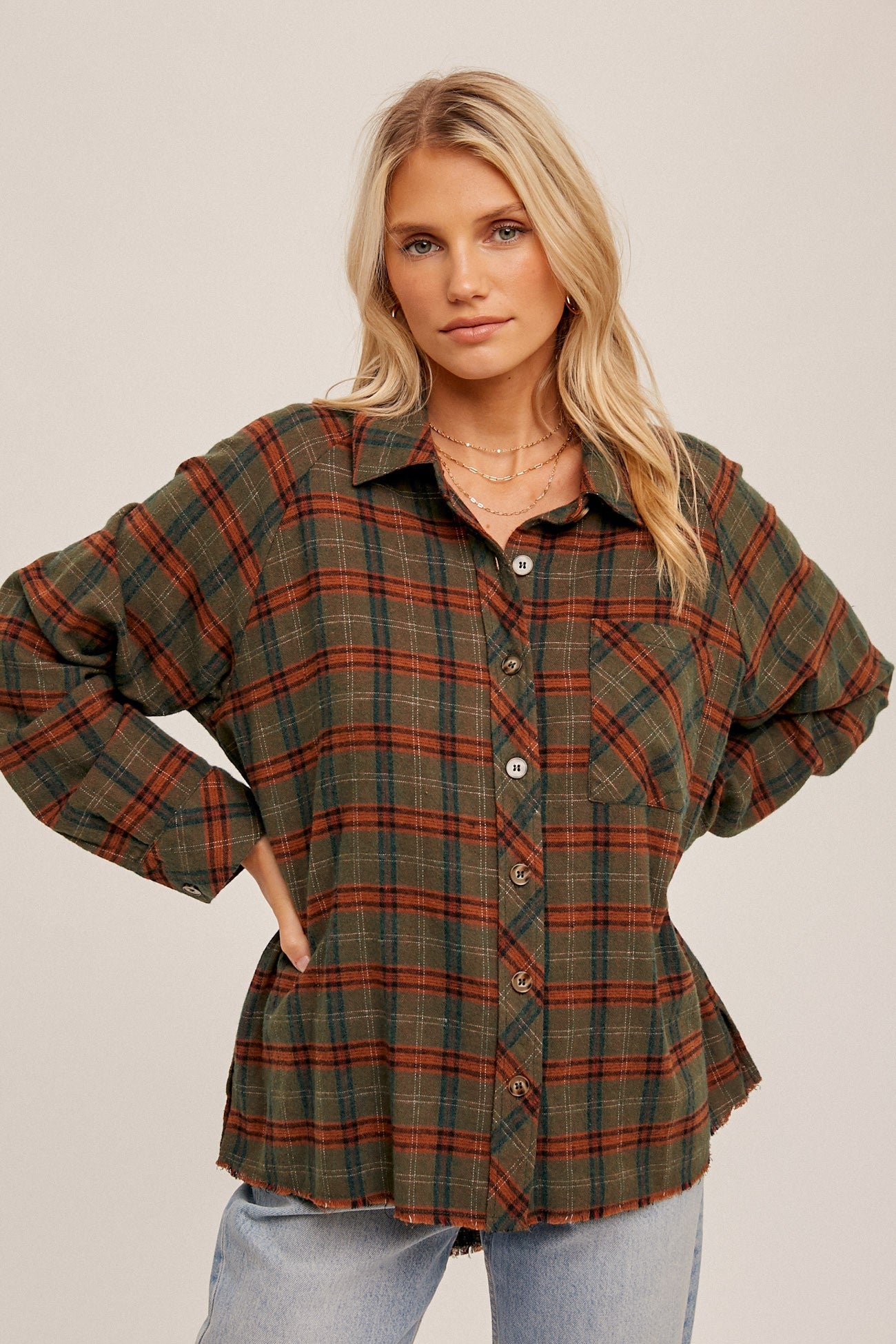 blonde woman wearing an oversized green and brown plaid flannel shirt with light wash jeans