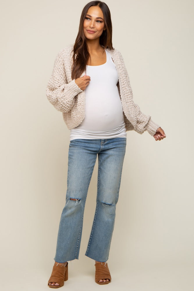 pregnant woman wearing cream knit cardigan white maternity tank top and distressed blue jeans