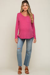 Pregnant woman wearing a pink long sleeve maternity top and distressed blue jeans with brown sandals