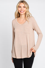 woman wearing a beige long sleeve v-neck ribbed top with a front pocket and black pants
