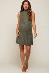 pregnant woman wearing olive green sleeveless cable knit maternity sweater dress and brown mules
