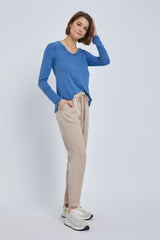 woman wearing blue long sleeve v-neck shirt and beige drawstring trousers with white sneakers