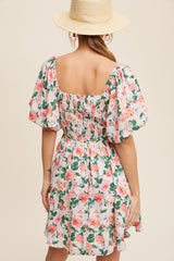 woman wearing a floral short dress with puff sleeves and a smocked back, styled with a straw hat
