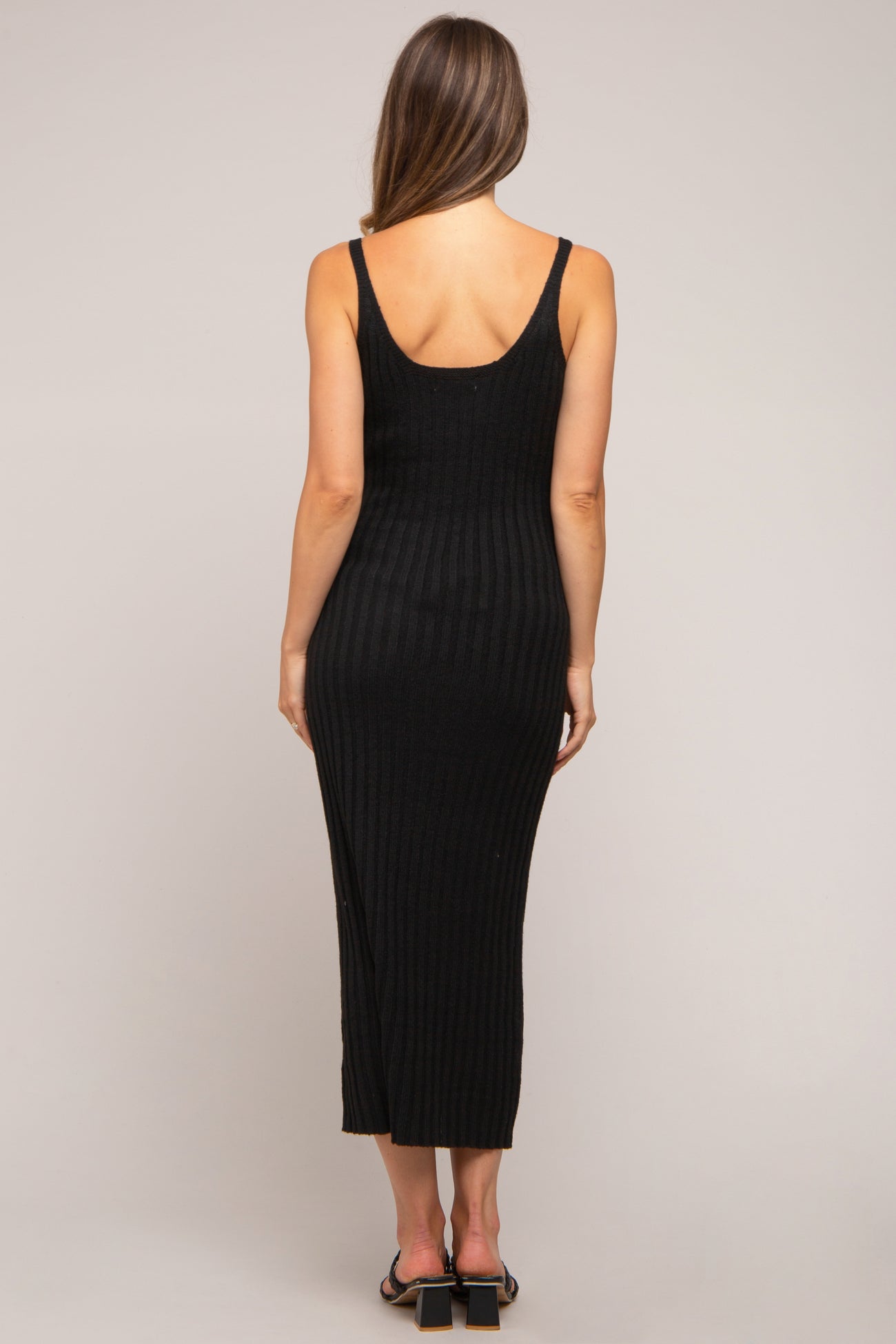 woman wearing a black ribbed maternity maxi dress, showing a fitted silhouette and spaghetti straps