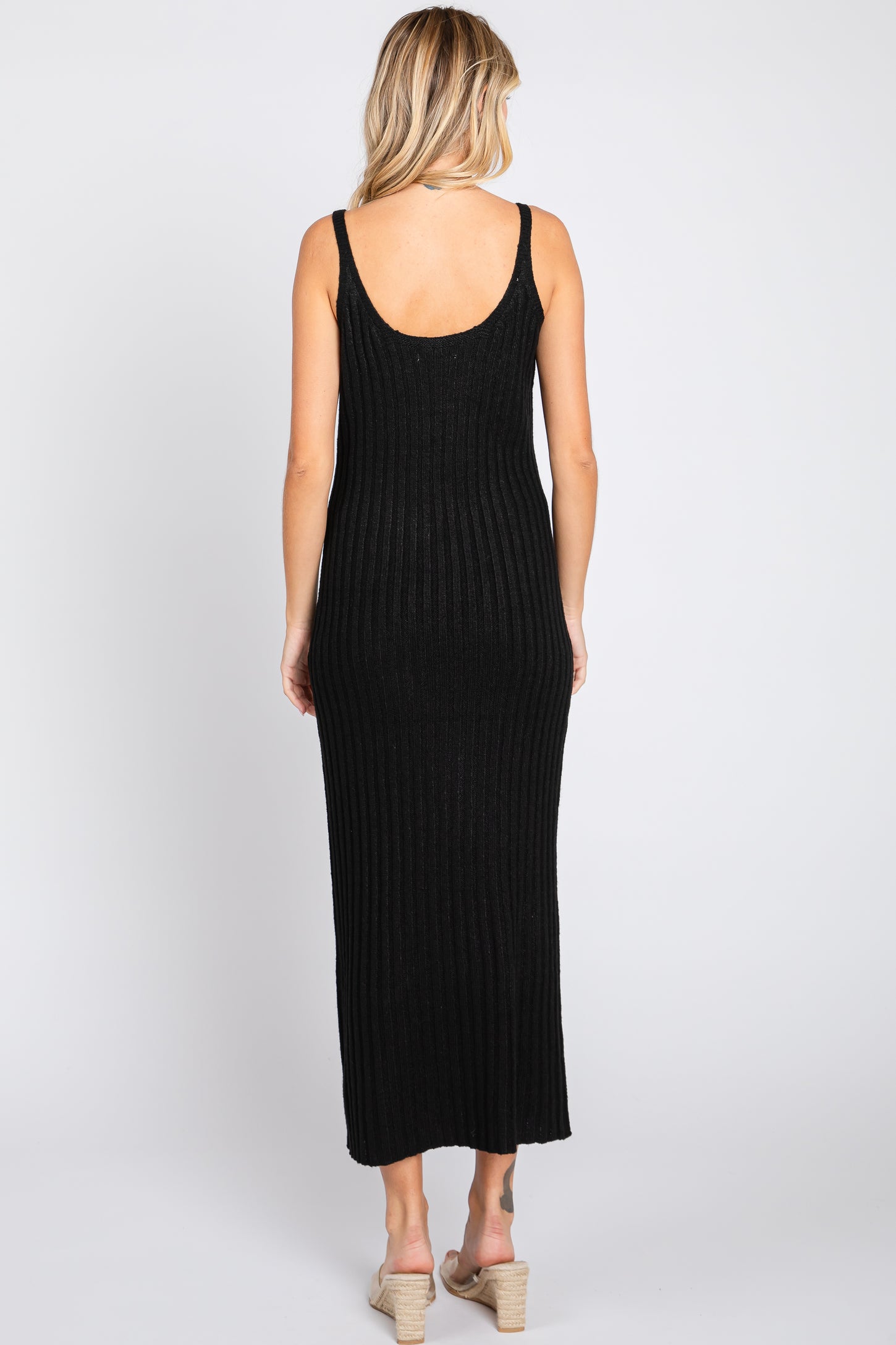 woman wearing a black ribbed maxi dress with a scoop back and a fitted silhouette