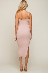 woman wearing a pink ribbed maternity dress with a mid-length fit and side slits, showing off a baby bump