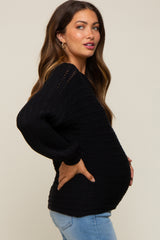 Pregnant woman in a black long sleeve maternity sweater and blue jeans posing in profile