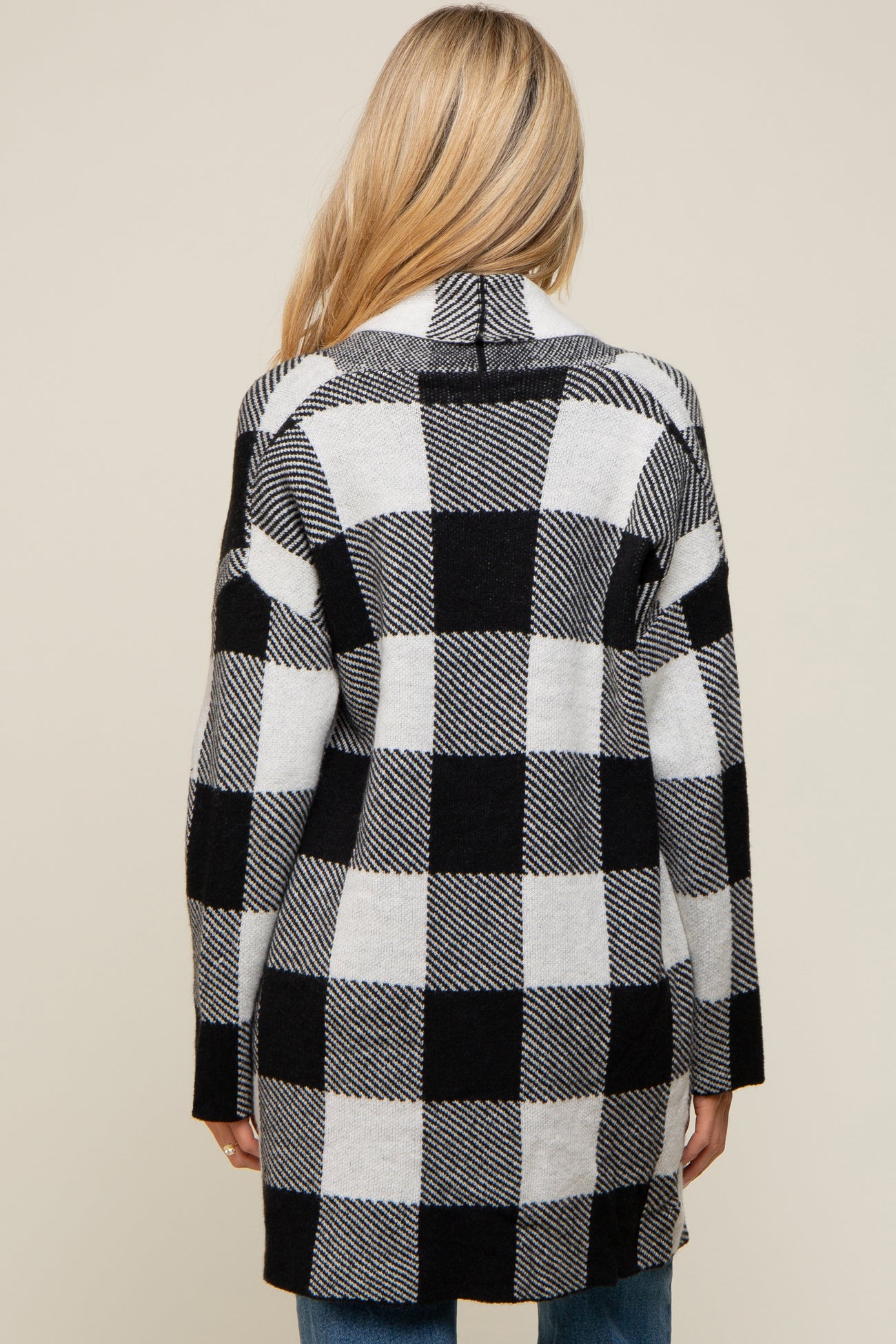Back view of a woman wearing a long black and white buffalo plaid cardigan sweater