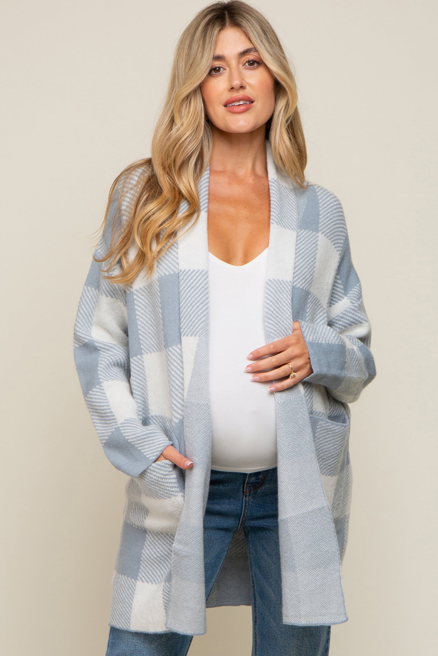 pregnant woman wearing a blue and white plaid maternity cardigan over a white top and jeans