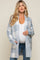 pregnant woman wearing a blue and white plaid maternity cardigan over a white top and jeans