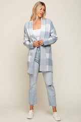 Woman wearing a light blue and white checkered cardigan with distressed jeans and white sneakers