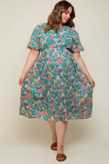 woman wearing a floral blue maternity plus dress with short sleeves and a flowing skirt, showcasing her baby bump