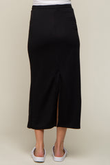 back view of a woman wearing a long black midi skirt with a back slit and white sandals