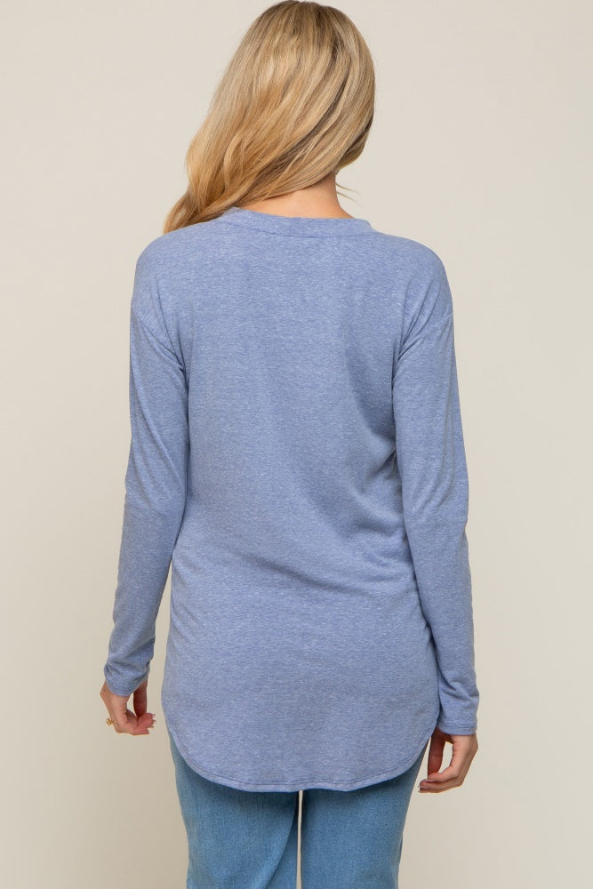 back view of a woman with blonde hair wearing a light blue long sleeve tunic top and jeans