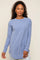 woman wearing a light blue long sleeve crewneck shirt with a curved hem and light wash jeans