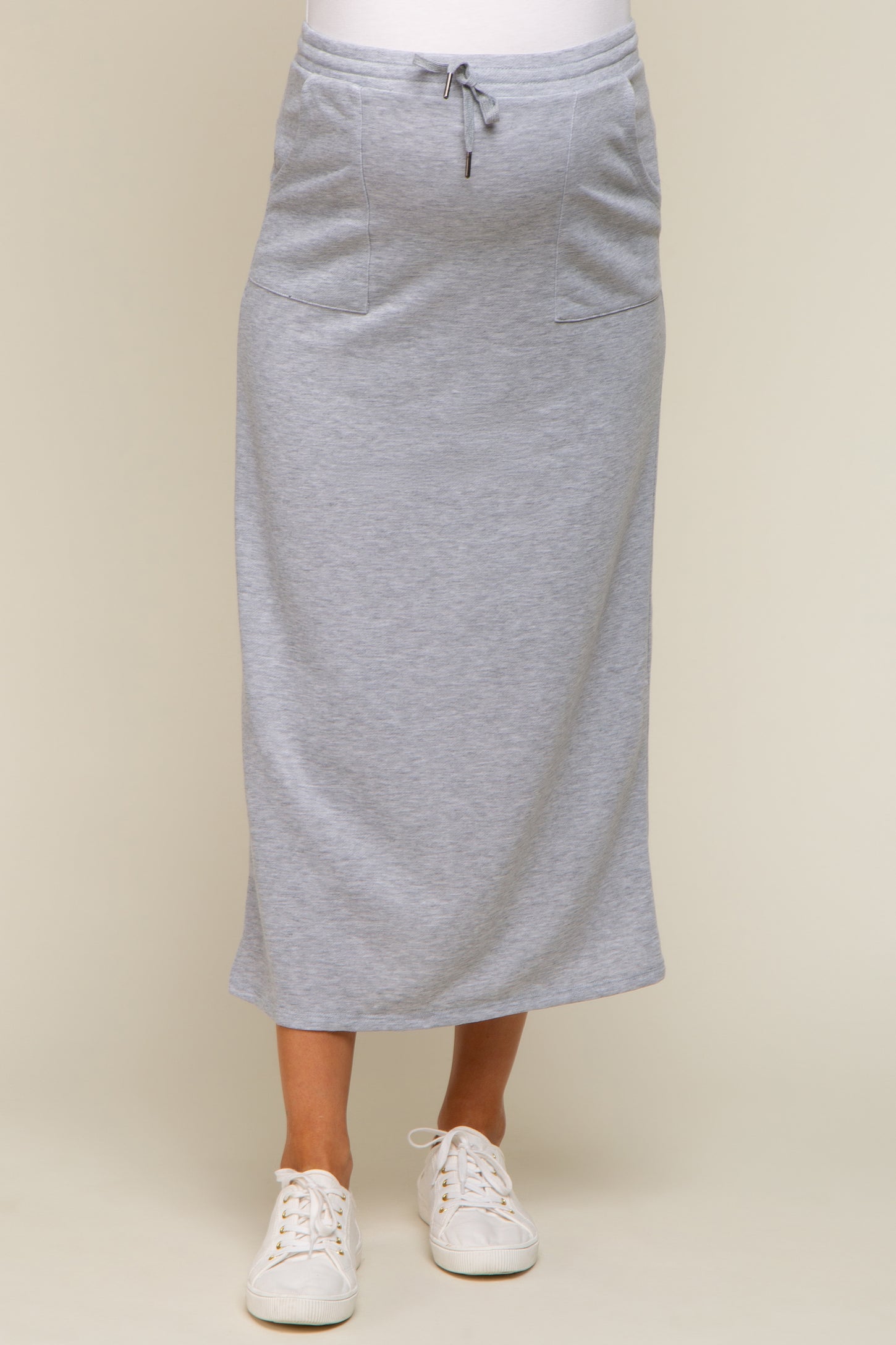 woman wearing a gray maternity maxi skirt with pockets and drawstring waist, paired with white sneakers