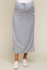 woman wearing a gray maternity maxi skirt with pockets and drawstring waist, paired with white sneakers