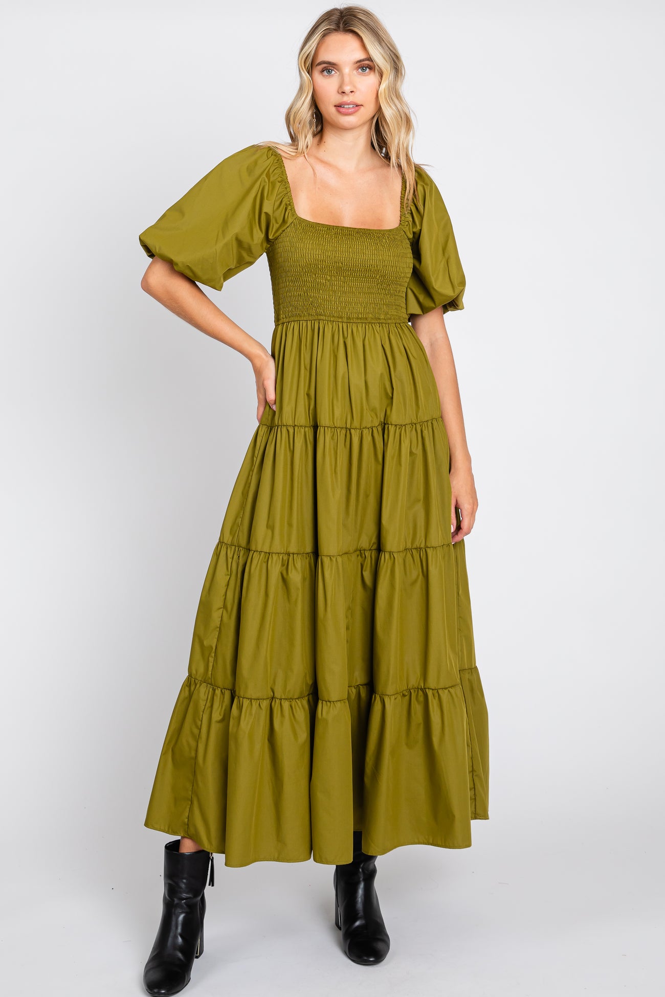 woman wearing olive green tiered maxi dress with smocked bodice and puff sleeves paired with black boots