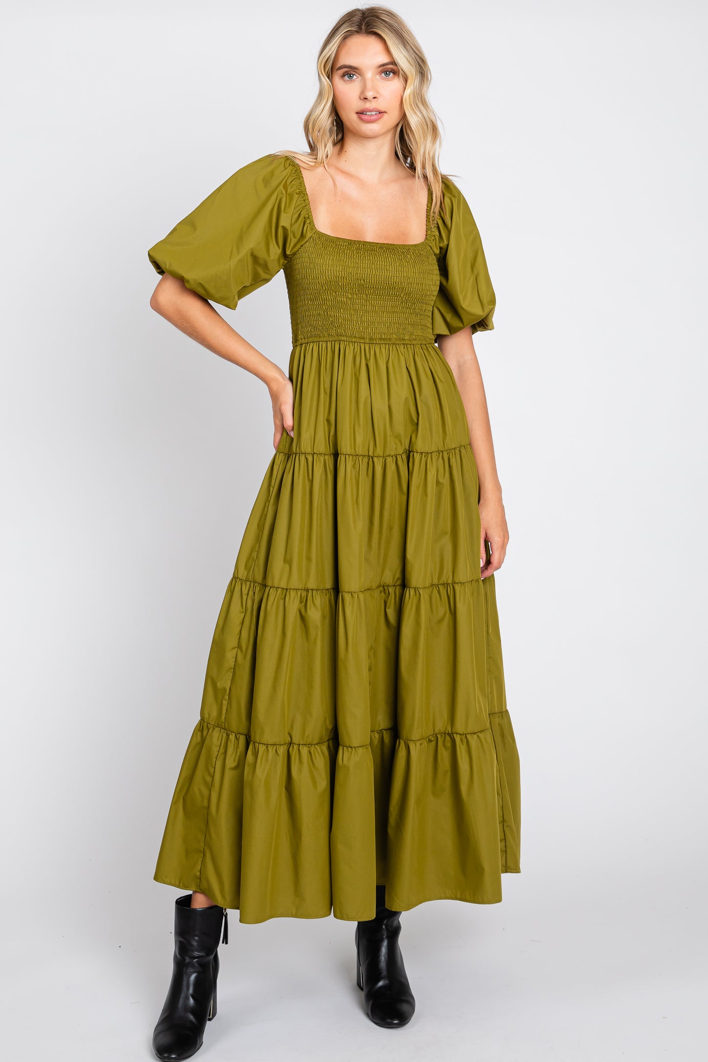woman wearing olive green tiered maxi dress with smocked bodice and puff sleeves paired with black boots