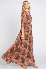 Woman wearing a long brown and orange paisley print maxi dress with flutter sleeves and tan heels