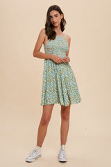 woman wearing a green floral sundress with a fitted bodice and flowy skirt, paired with white sneakers