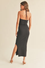 woman wearing a black ribbed midi dress with a back tie and side slit, shown from the back