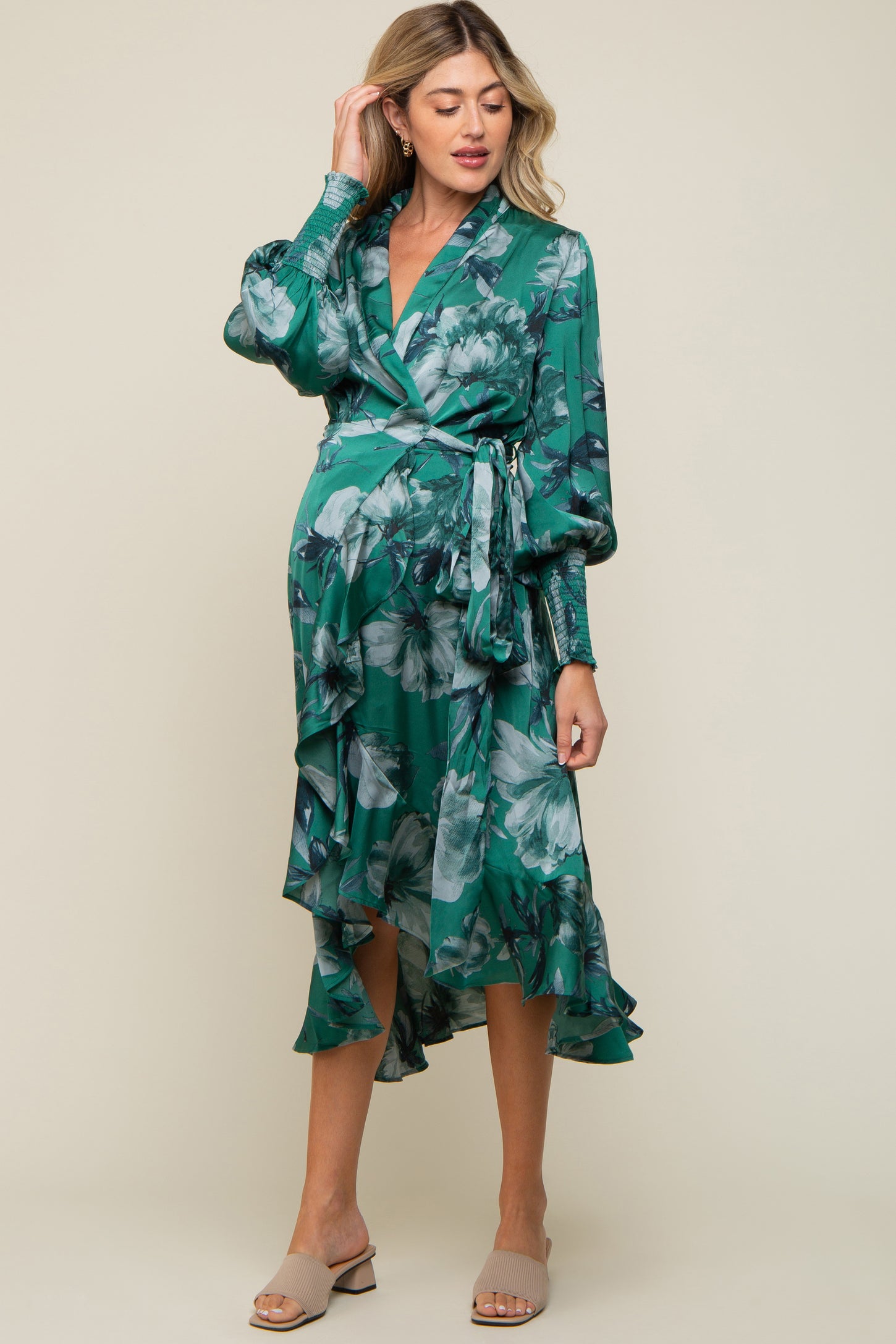 woman wearing a green floral wrap maternity dress with ruffle details and a baby bump visible
