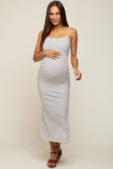 woman wearing a striped maternity maxi dress with spaghetti straps and gently holding her baby bump