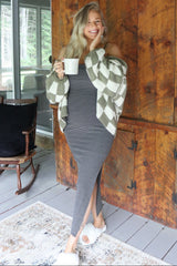woman wearing a gray striped maxi dress with a thigh-high slit, layered with a cream and olive green checkered cardigan