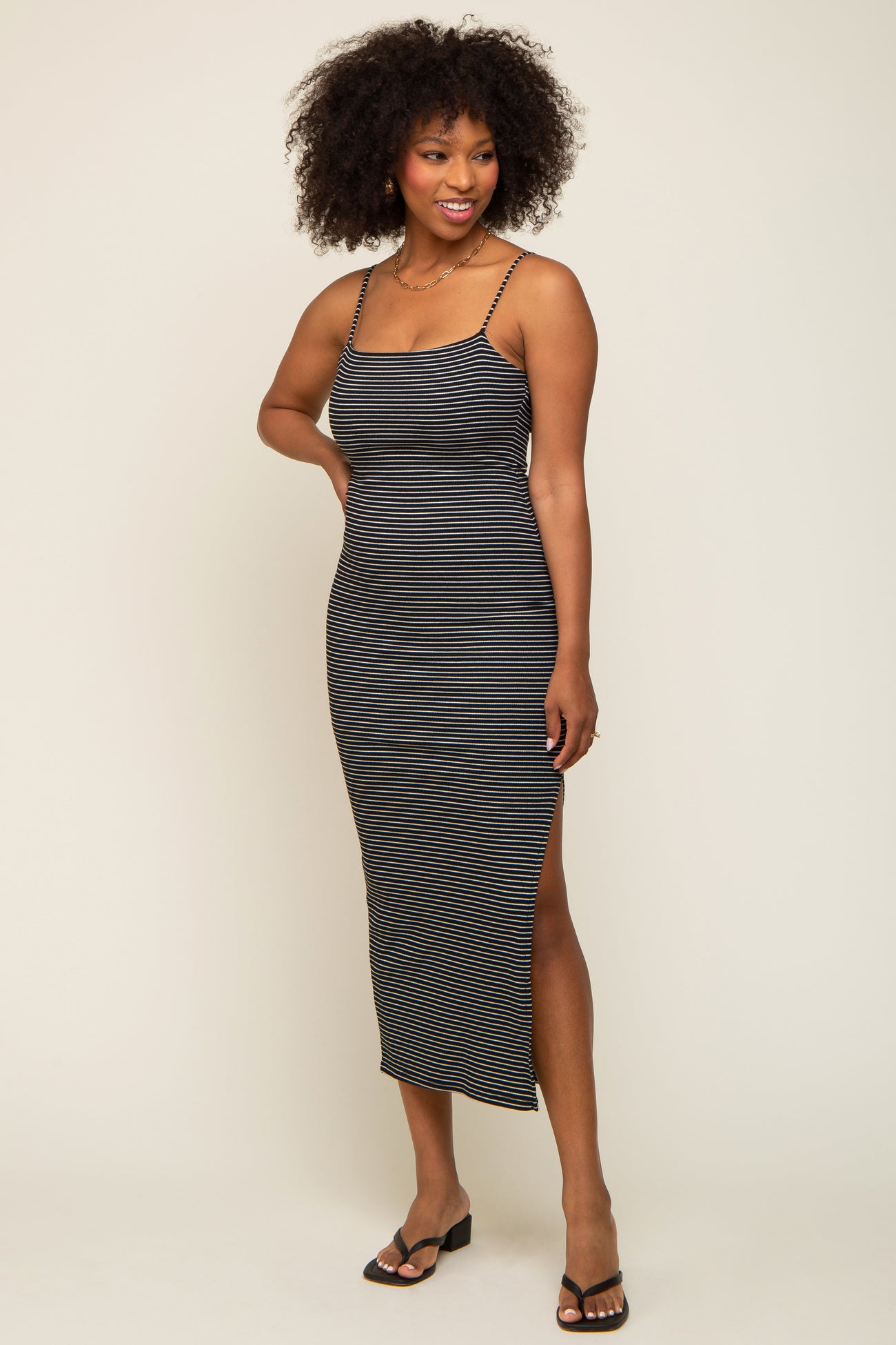woman wearing a black and white striped midi dress with a side slit and adjustable straps
