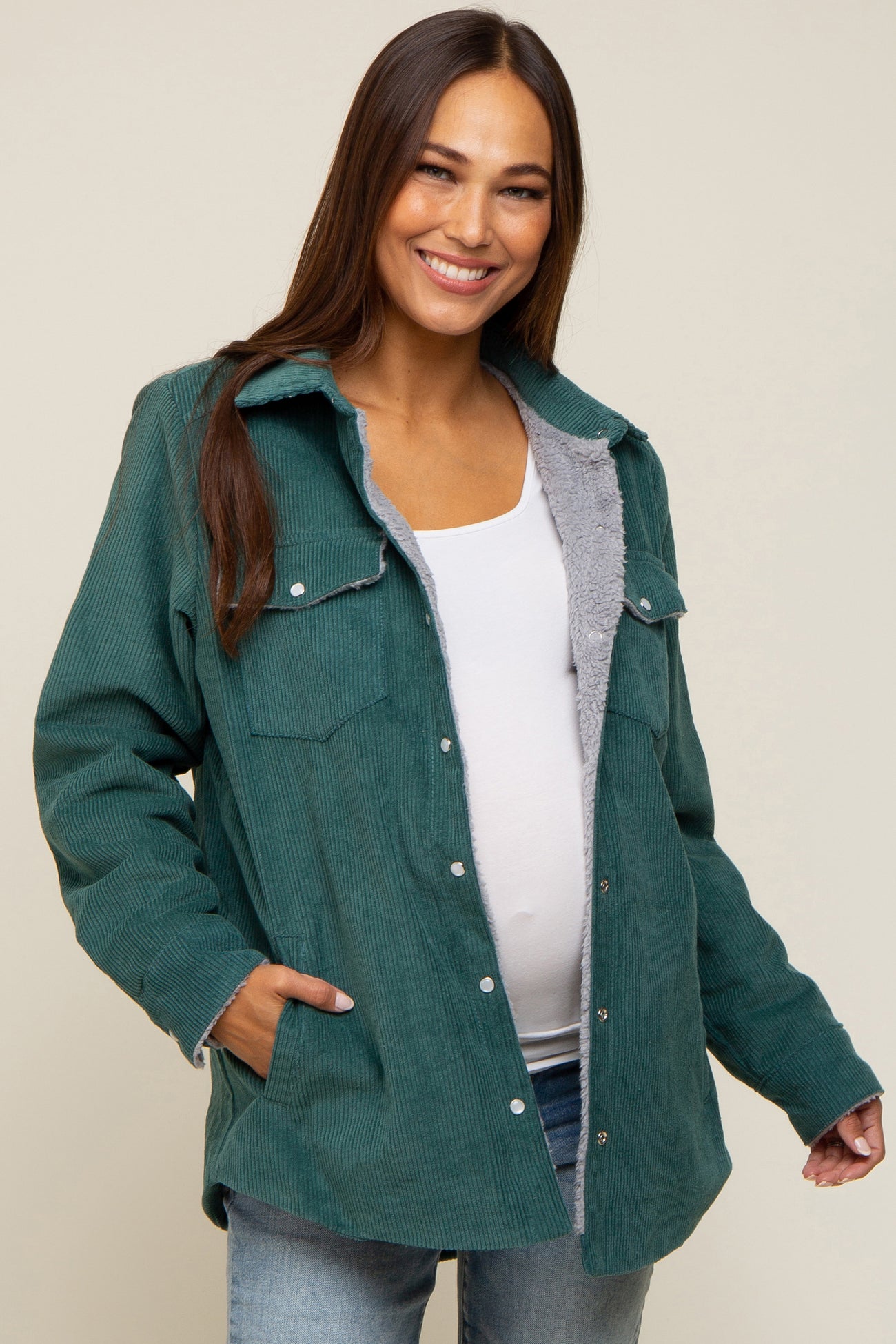 woman wearing a green corduroy maternity jacket with a fleece lining and a visible baby bump