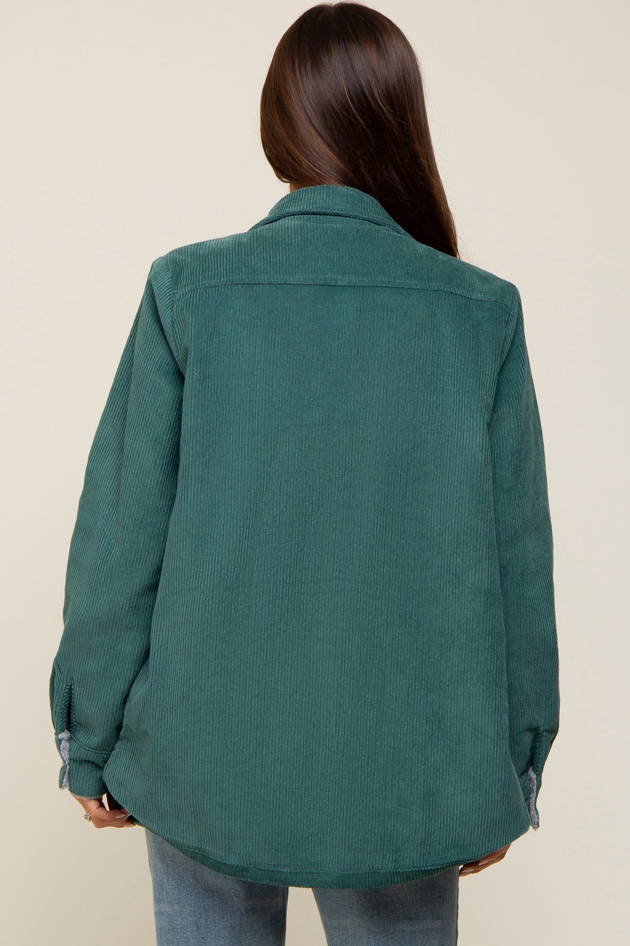 woman wearing a green corduroy maternity jacket, seen from the back
