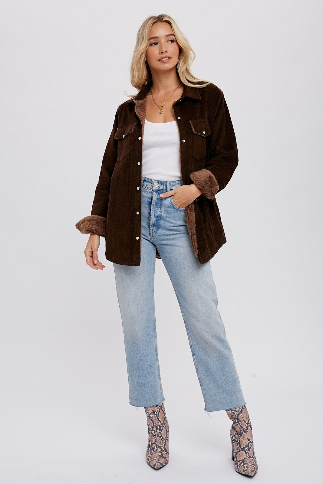 woman wearing brown corduroy jacket with faux fur lining, light wash jeans, and snakeskin boots