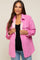 woman wearing a pink corduroy jacket with faux fur lining over a black top and blue jeans