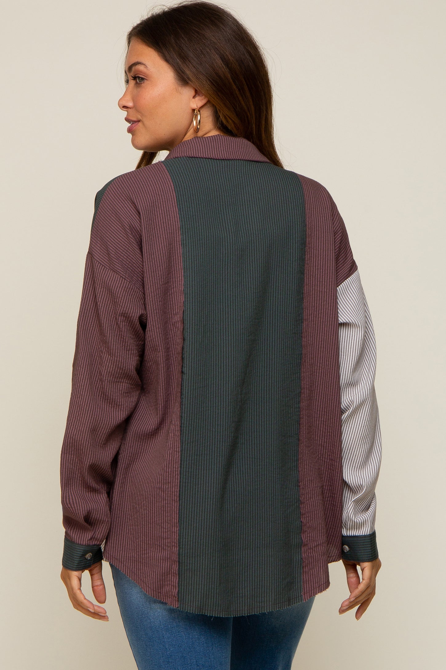 Woman wearing a colorblock corduroy button down shirt with purple, green, and white striped panels.