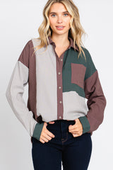 Woman wearing a color block corduroy button-down shirt in brown, green, and striped patterns with dark jeans