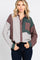 Woman wearing a color block corduroy button-down shirt in brown, green, and striped patterns with dark jeans