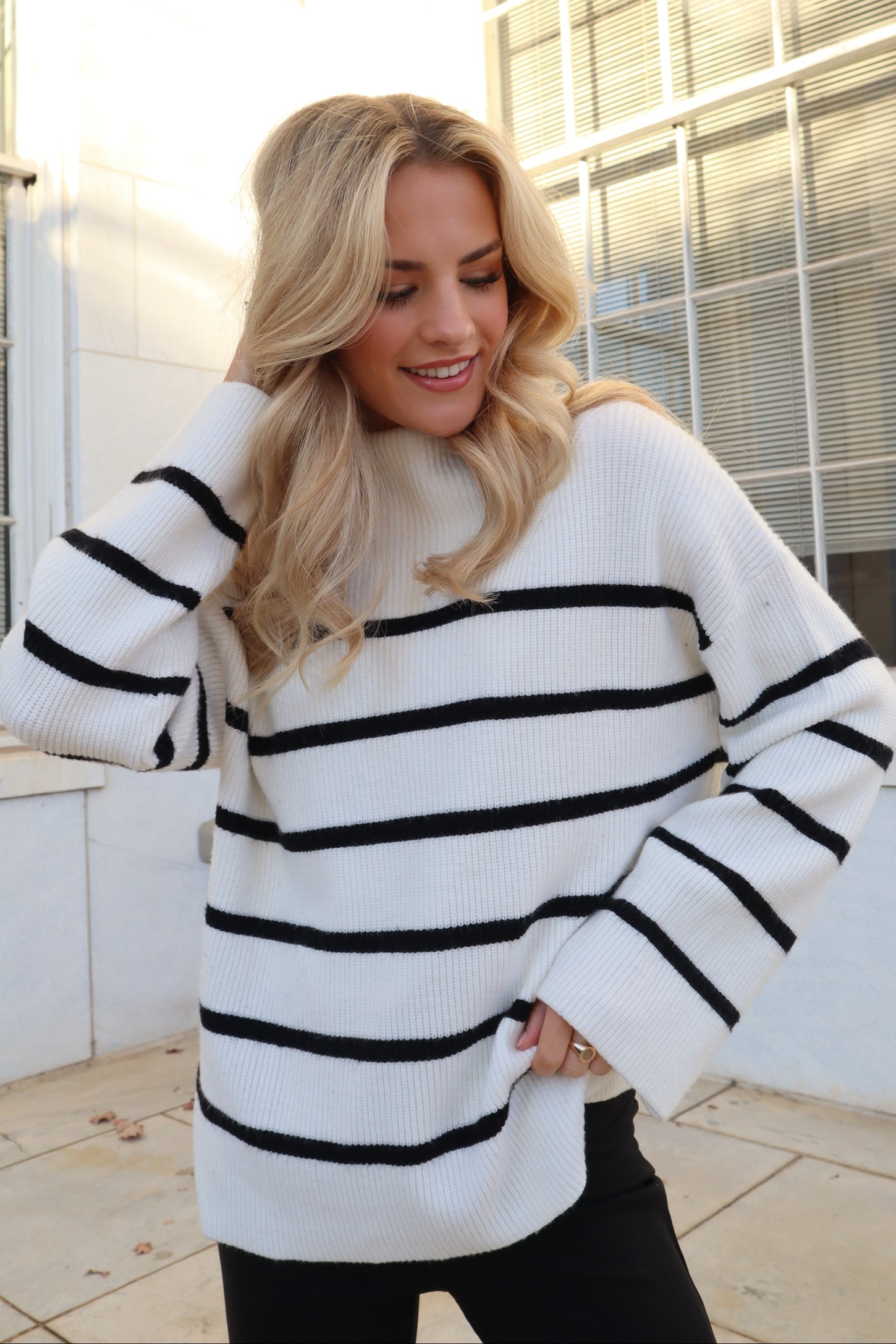 woman wearing a cream and black striped oversized sweater with relaxed fit and wide sleeves