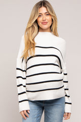 woman wearing a white and black striped maternity sweater with relaxed fit and long sleeves, showing her baby bump