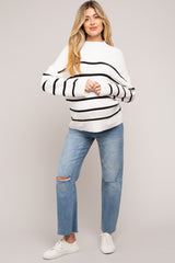 woman wearing a striped white and black maternity sweater with loose sleeves and distressed light blue jeans