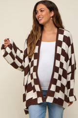 woman wearing a brown and white checkered maternity cardigan with a visible baby bump, paired with a white top and jeans
