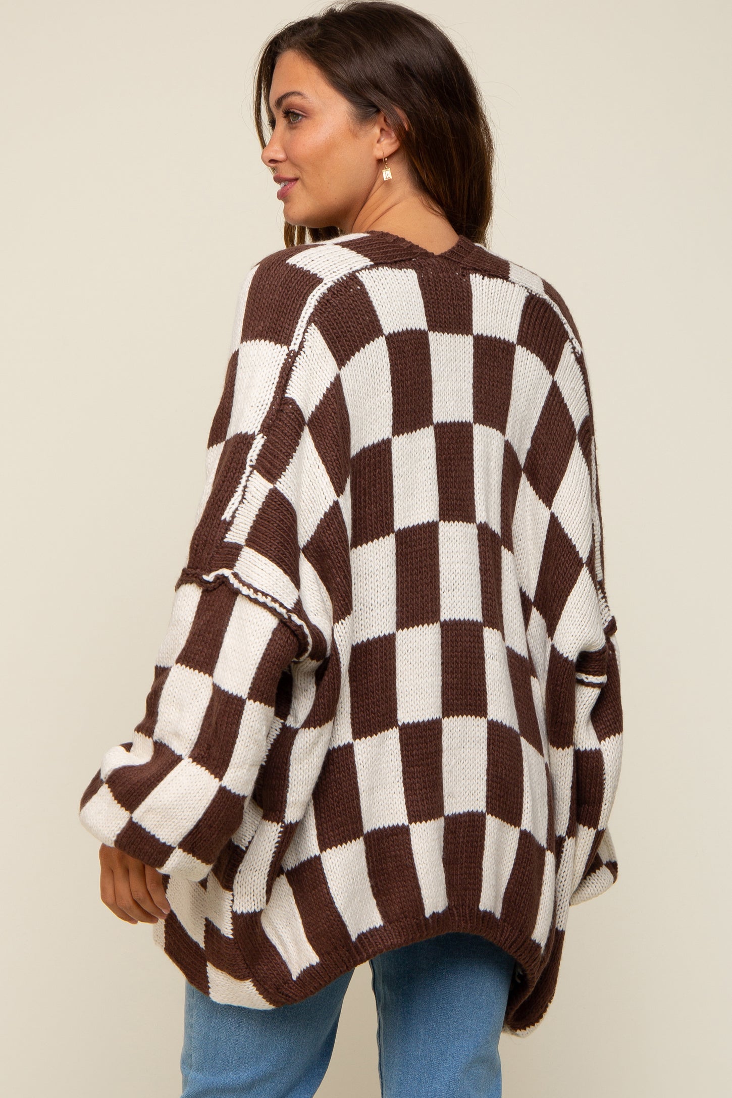 woman wearing a brown and white checkered oversized maternity sweater with loose sleeves