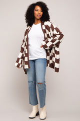 woman wearing a brown and cream striped oversized cardigan, white t-shirt, and ripped light blue jeans with ankle boots