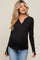woman wearing a black long sleeve maternity top with a henley neckline and buttons, showing her baby bump